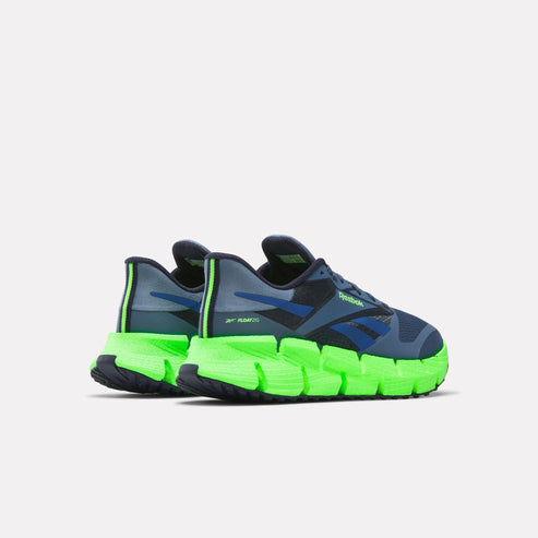 Low-top athletic shoes in dark blue, with green zigzag soles and green heel accent.