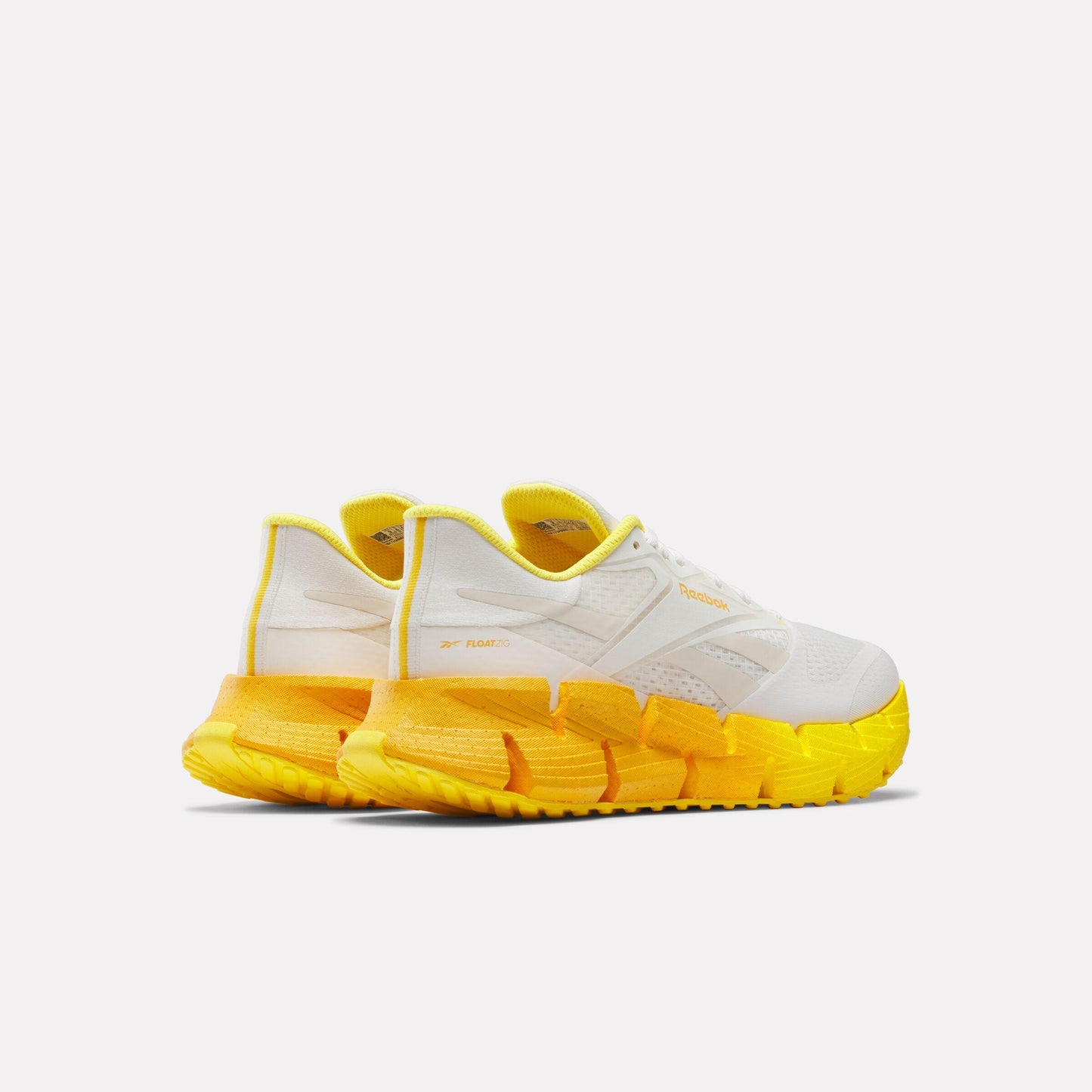 Rear view of white shoes with thick yellow zigzag sole.