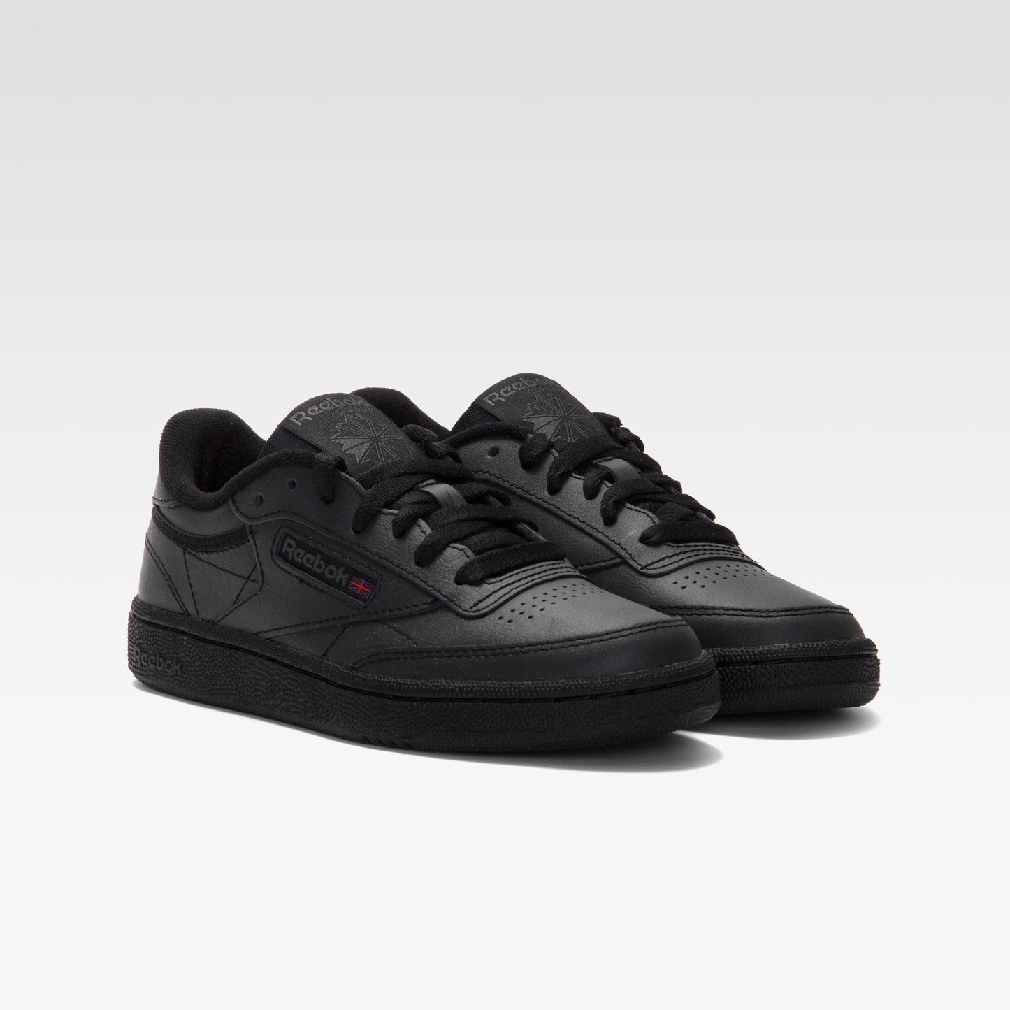 Pair of matte black, leather sneakers with black laces and a thin red stripe detail.