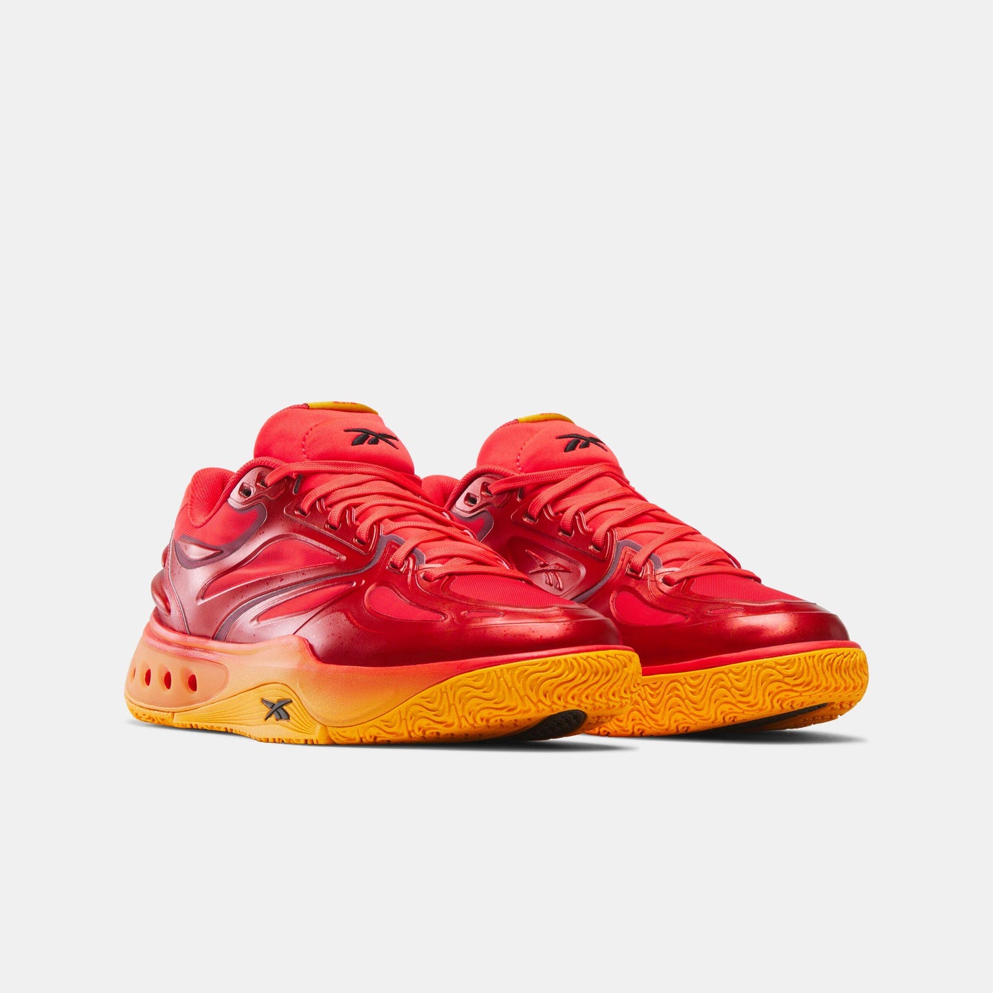 Pair of glossy red high-top basketball shoes with orange outsoles.