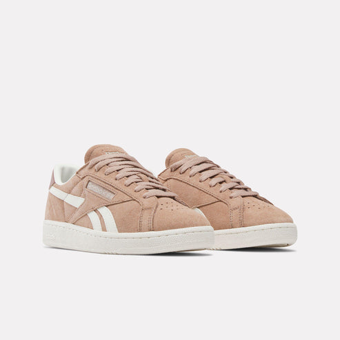 Two low-rise, tan suede sneakers with white accents, rubber soles, and laces.