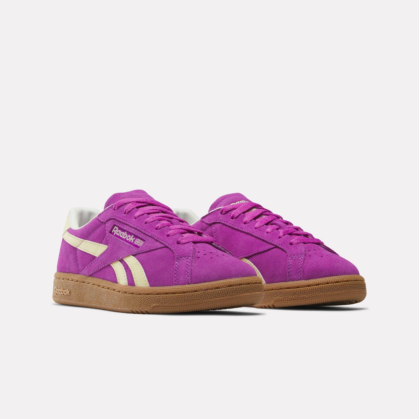 Low profile magenta sneakers with gum sole and cream stripes.