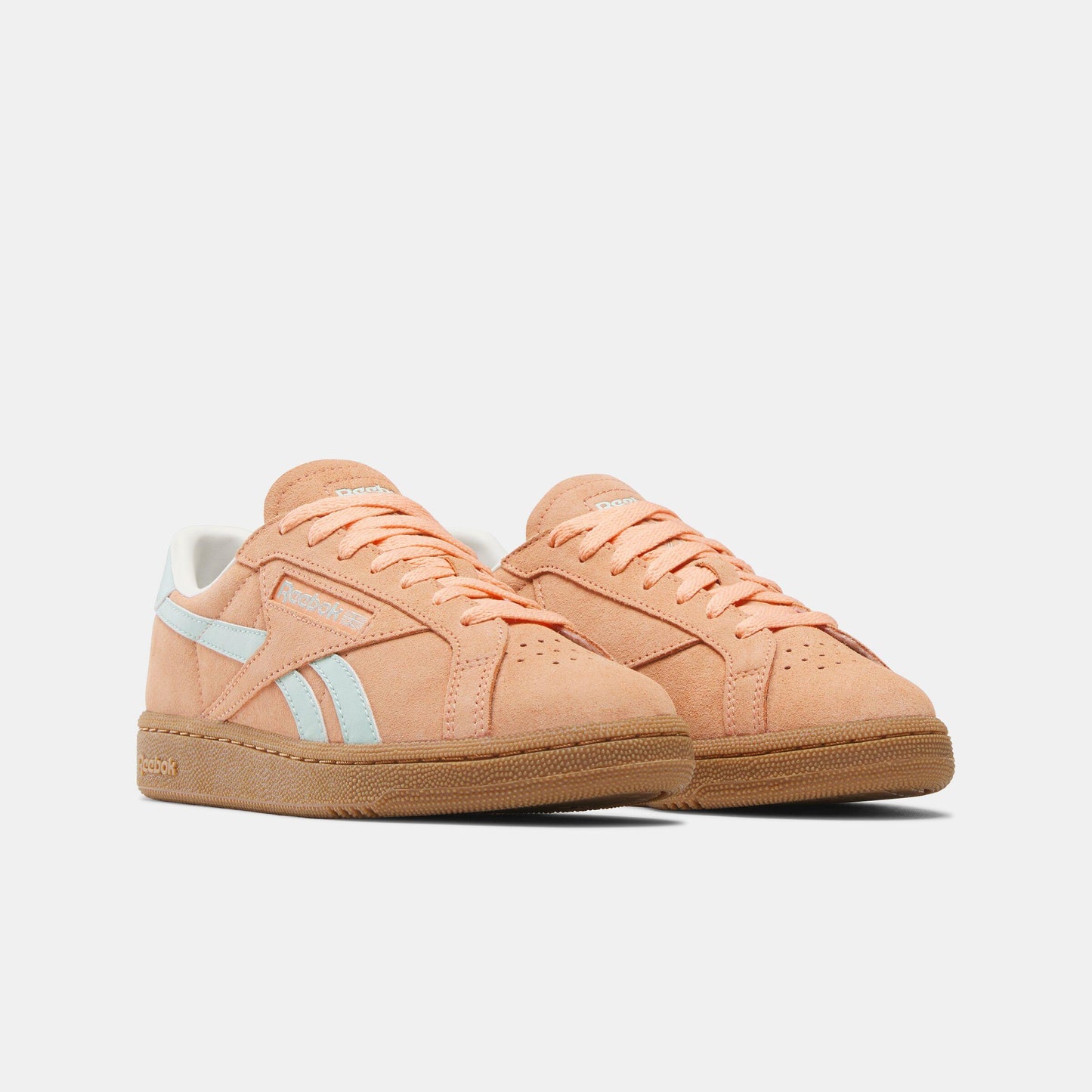 Pair of salmon-colored tennis shoes with gum soles and light blue stripes.