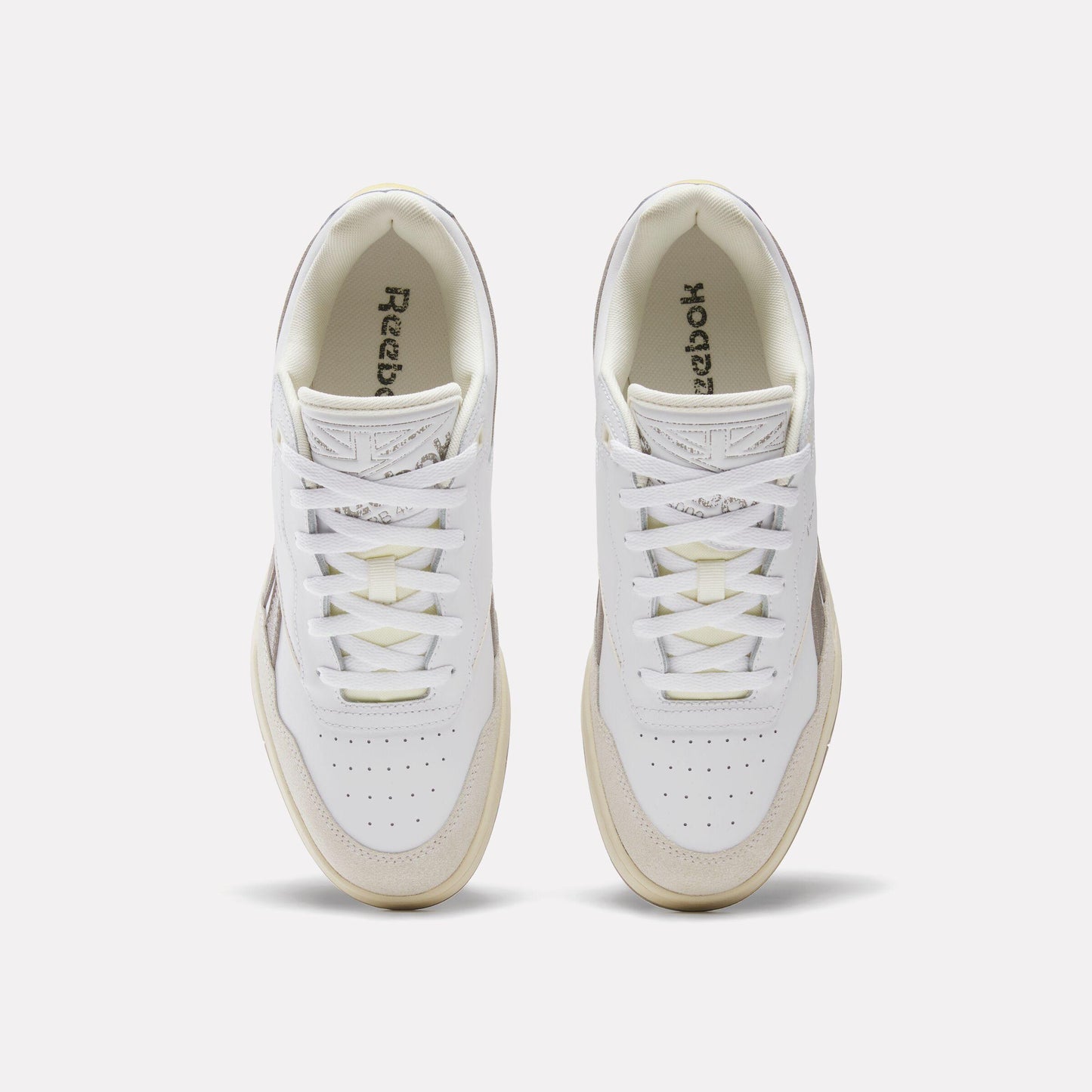 Overhead view of a pair of white leather sneakers with "Reebok" printed on the insole.