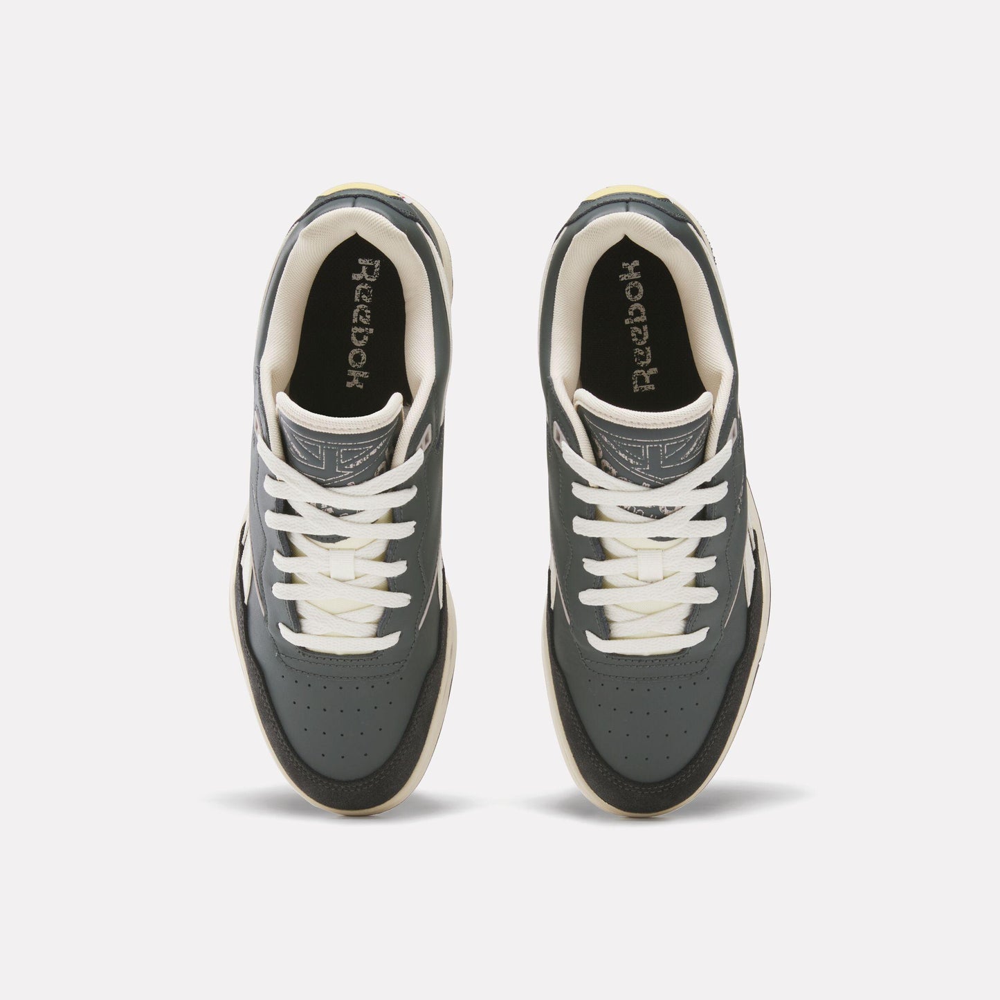 Overhead view of dark gray sneakers with white laces and "Reebok" branding on the tongue.