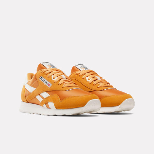 Pair of orange athletic shoes with white stripes and laces.