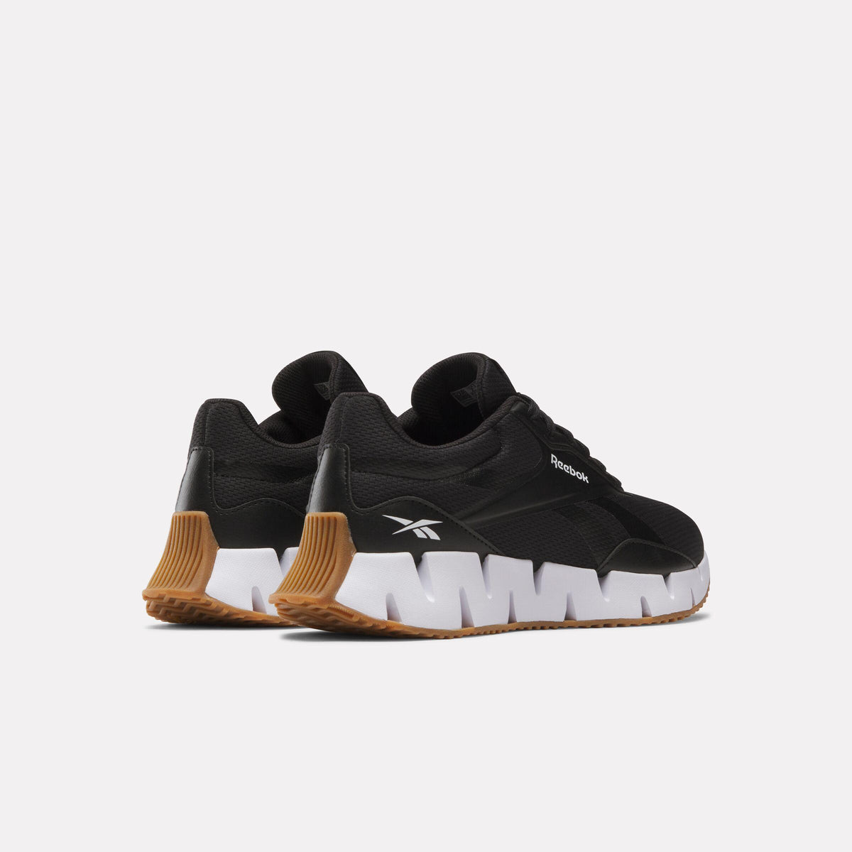 Rear view of low-top black Reebok shoe with white zigzag sole and brown heel.