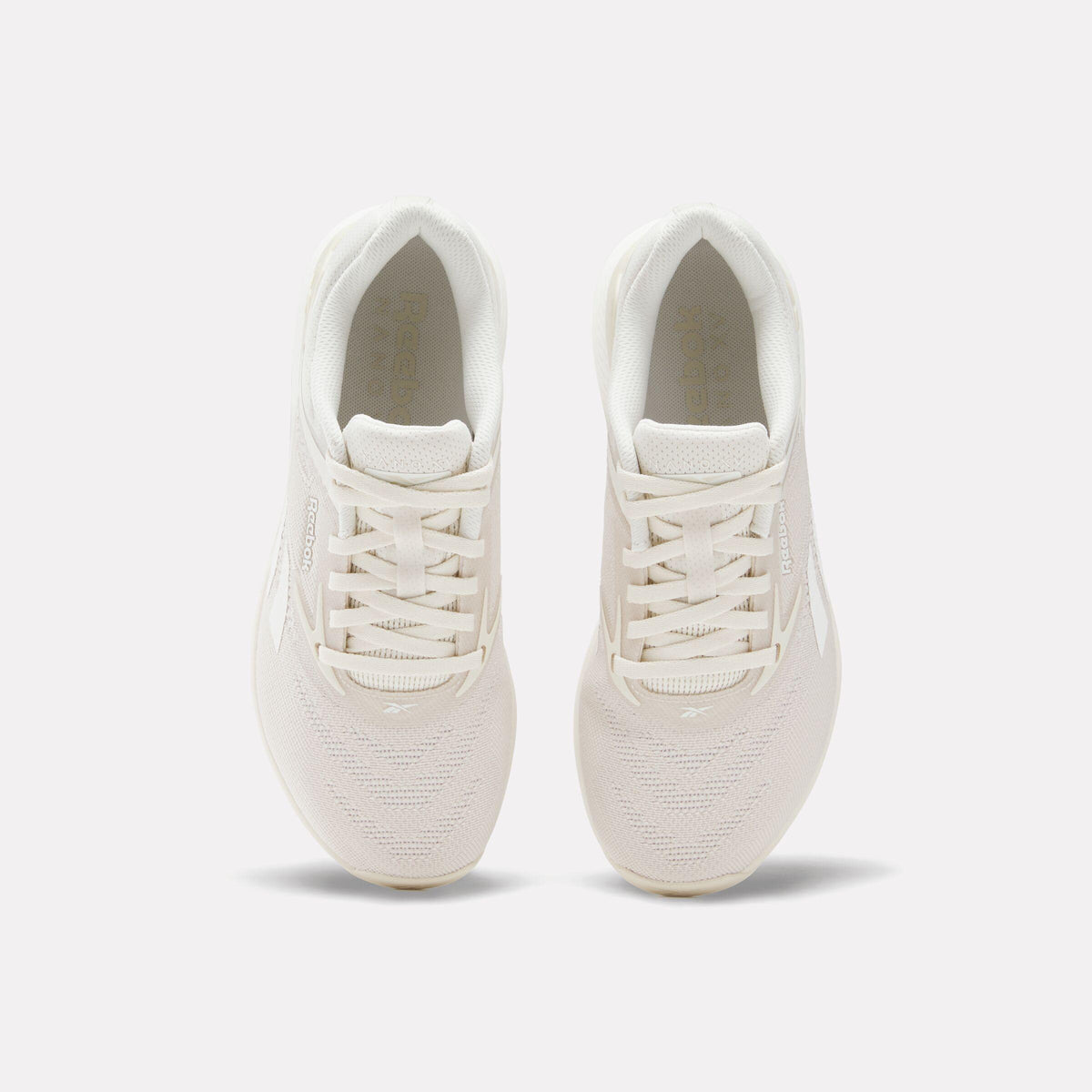 Overhead view of a pair of athletic shoes in off-white with a padded tongue and white laces.
