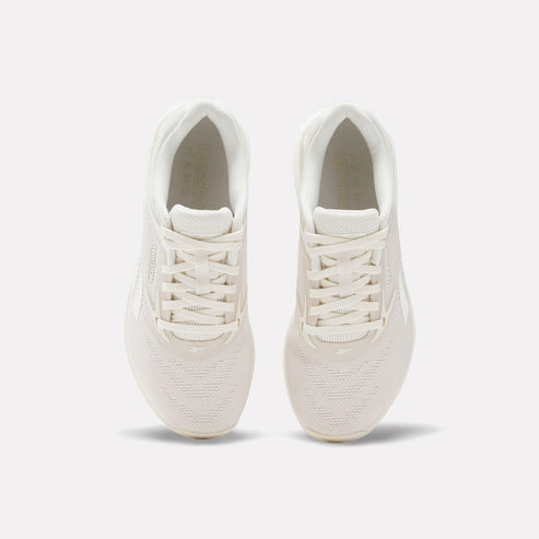 Overhead view of a pair of athletic shoes in off-white with a padded tongue and white laces.