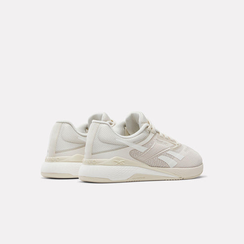 Angled view of white Reebok sneaker with mesh detailing and raised sole.