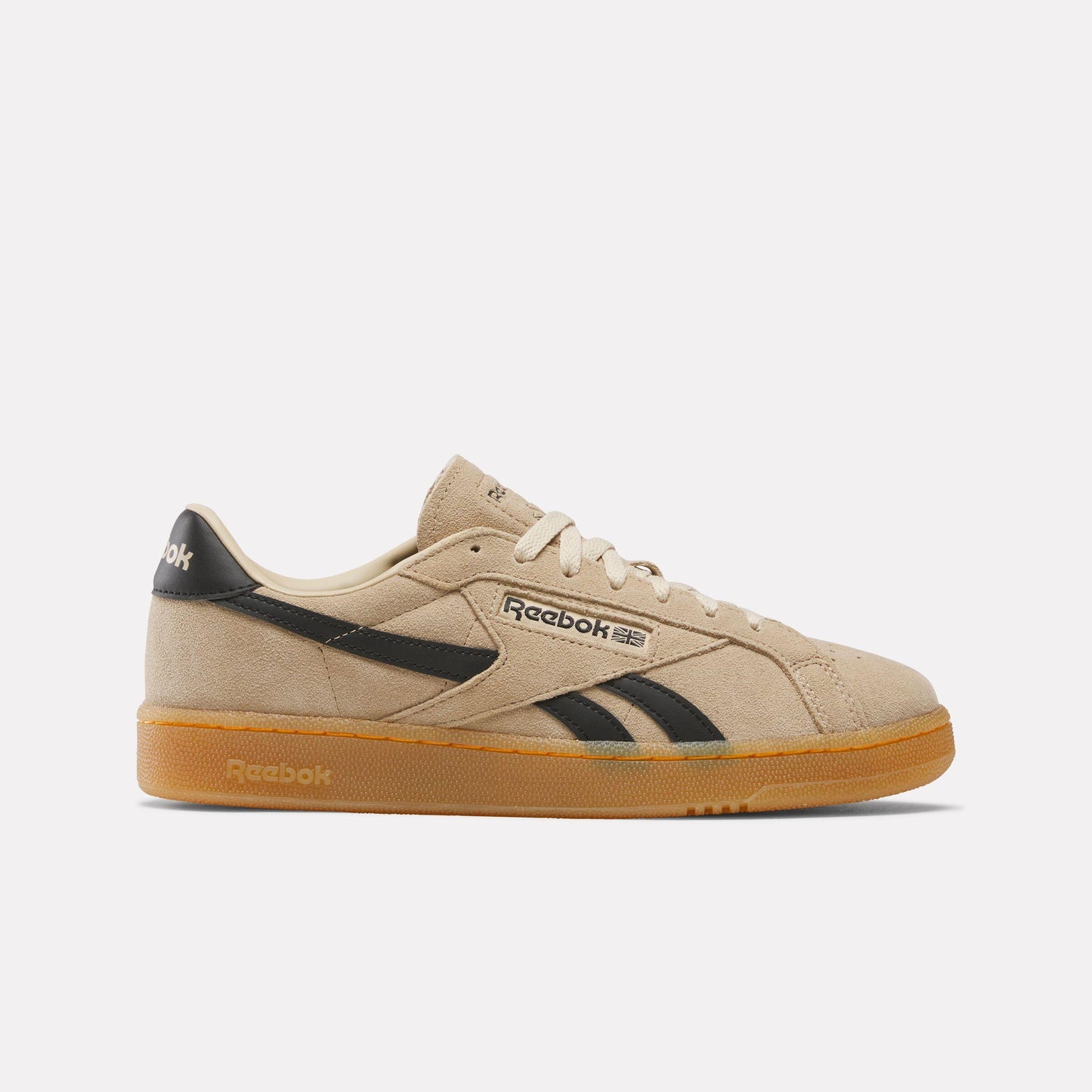 Tan suede low-top sneaker with black accents and a gum sole. The word "Reebok" and its logo are written on the side.