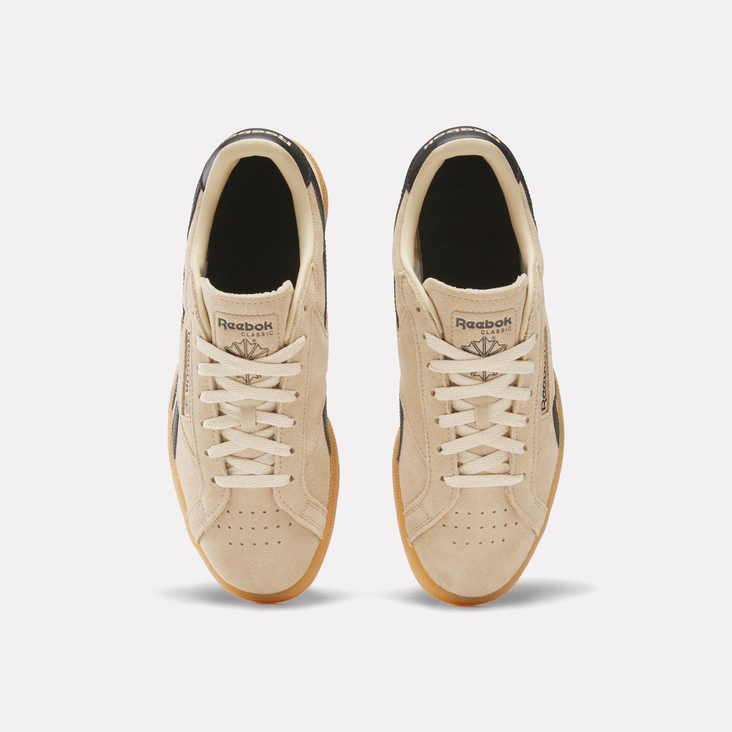 Top-down view of two light brown tennis shoes with light brown rubber soles and white laces.