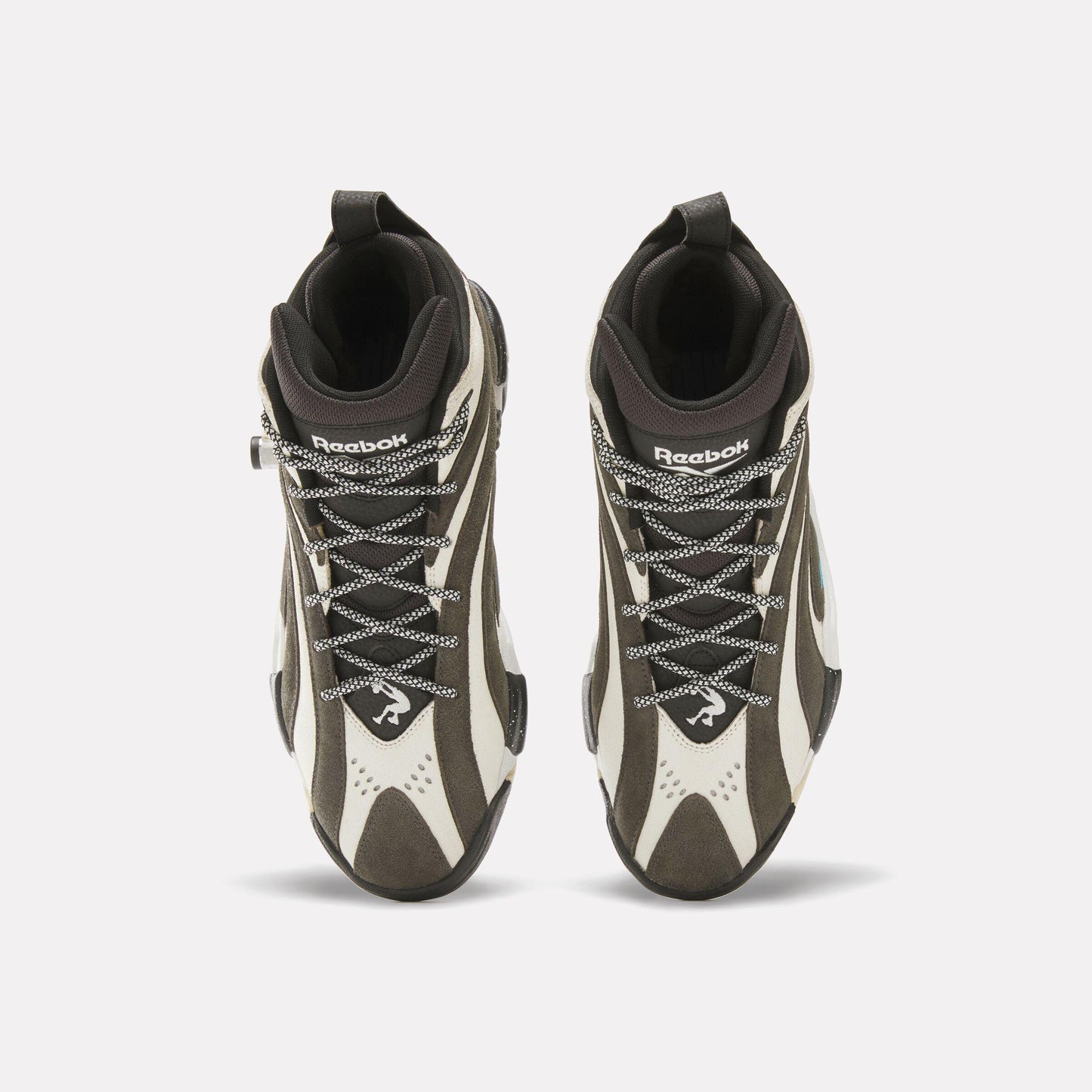 Top-down view of high-top shoes: black and white uppers, patterned laces, Reebok branding on the tongue.
