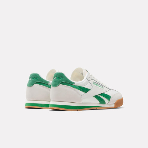 Low-profile off-white sneakers with green accents and brown soles.