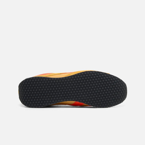 The sole of a shoe is black with small bumps, while the rest of the shoe is orange.