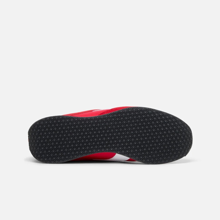 Red sneaker sole with small black circles for traction.