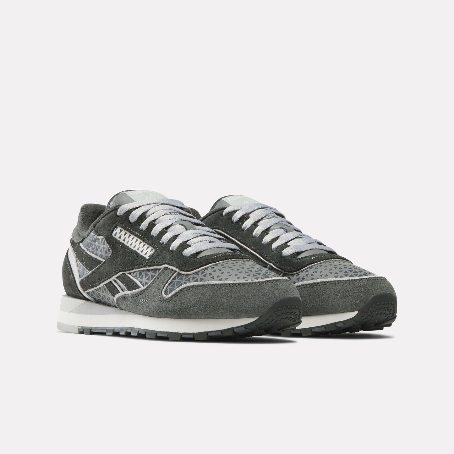 Two gray sneakers with white accents, featuring suede and patterned mesh.