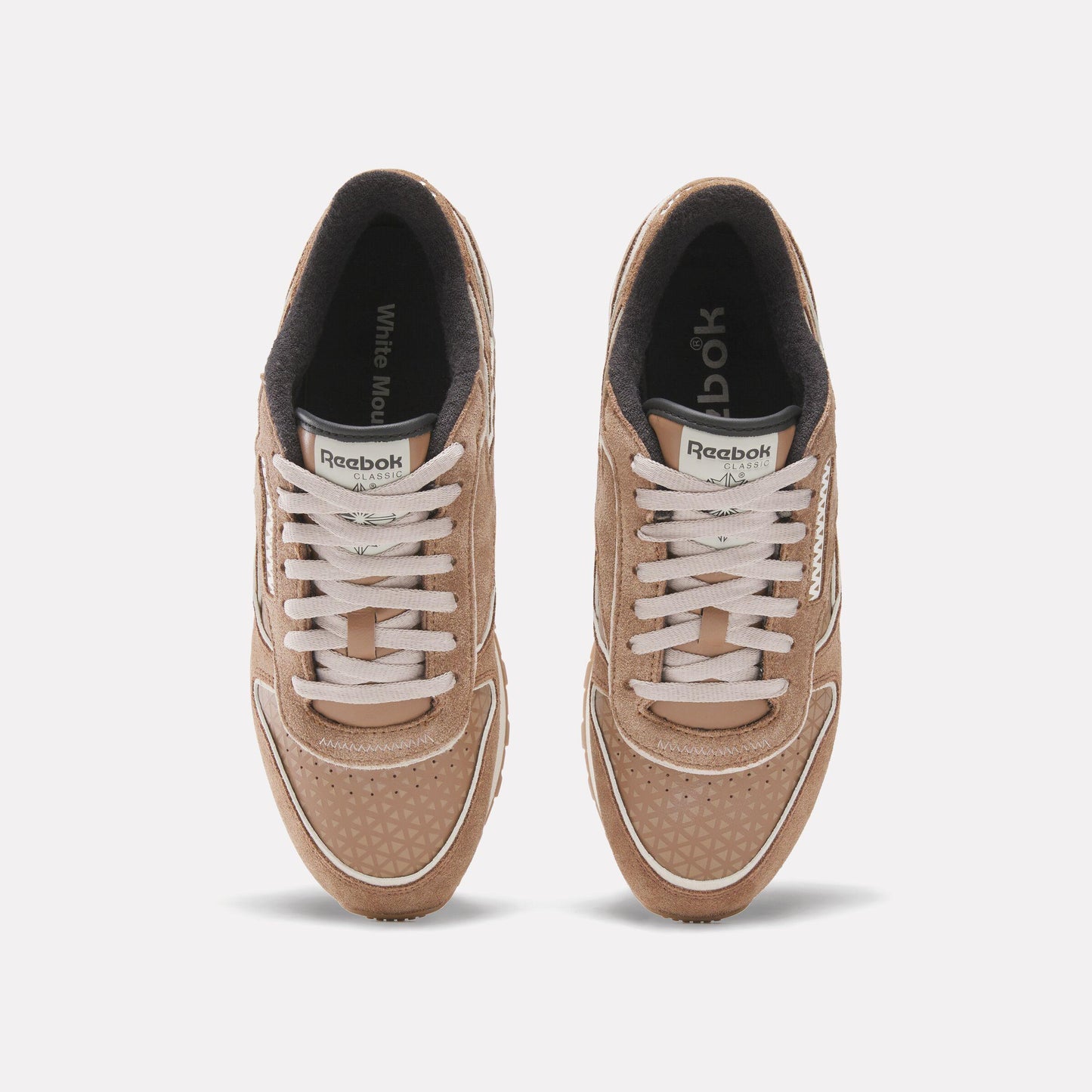 Top-down view of tan suede sneakers with white laces and trim.
