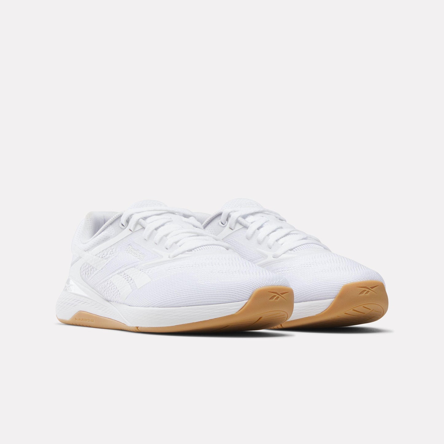 Pair of white athletic shoes with tan soles and white laces.