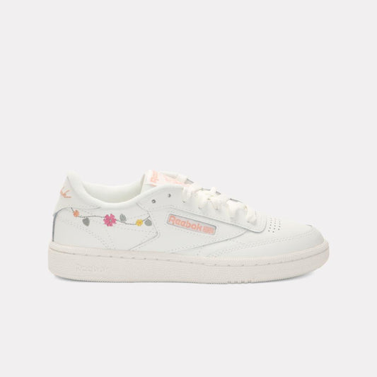 White sneaker with a light pink logo and colorful flower details.