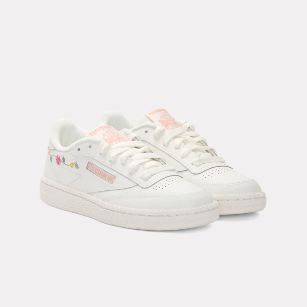 Pair of low top, all white sneakers with floral details on the side and on the tongue