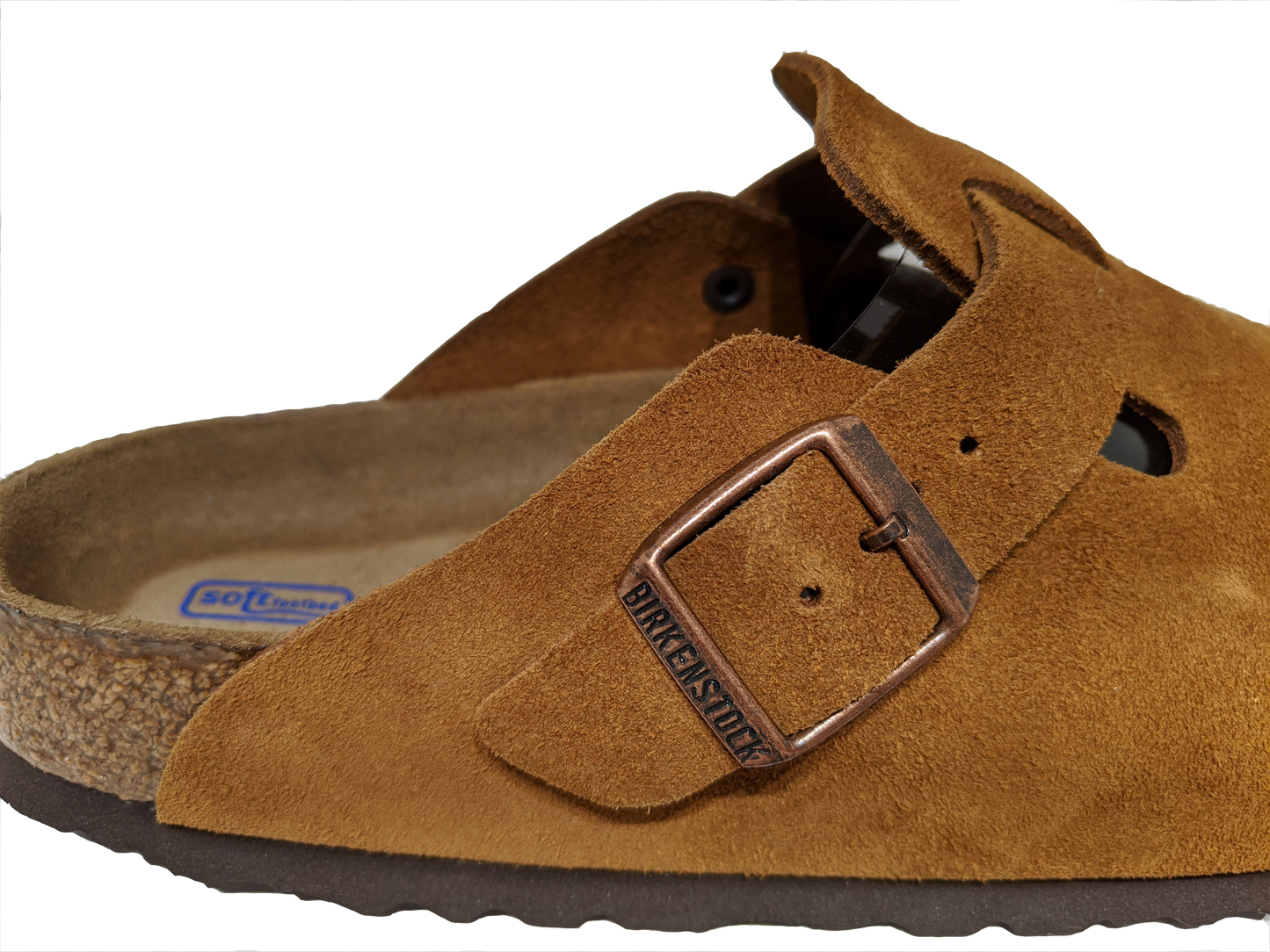 Close-up of a brown suede leather clog with a metal buckle.