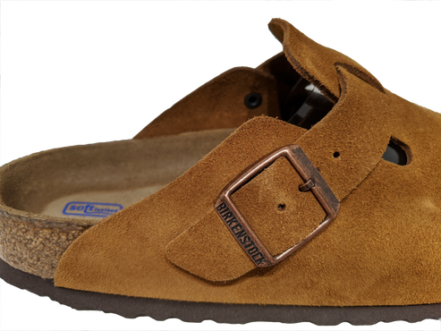 Close-up of a brown suede leather clog with a metal buckle.