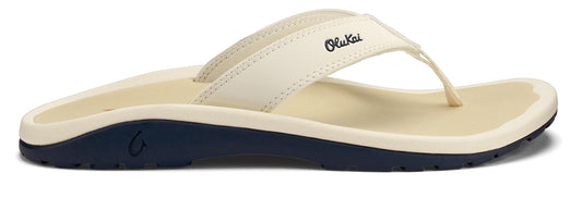 A flip-flop with light-colored straps and sole on a navy blue base; the brand name "OluKai" is visible on the side.