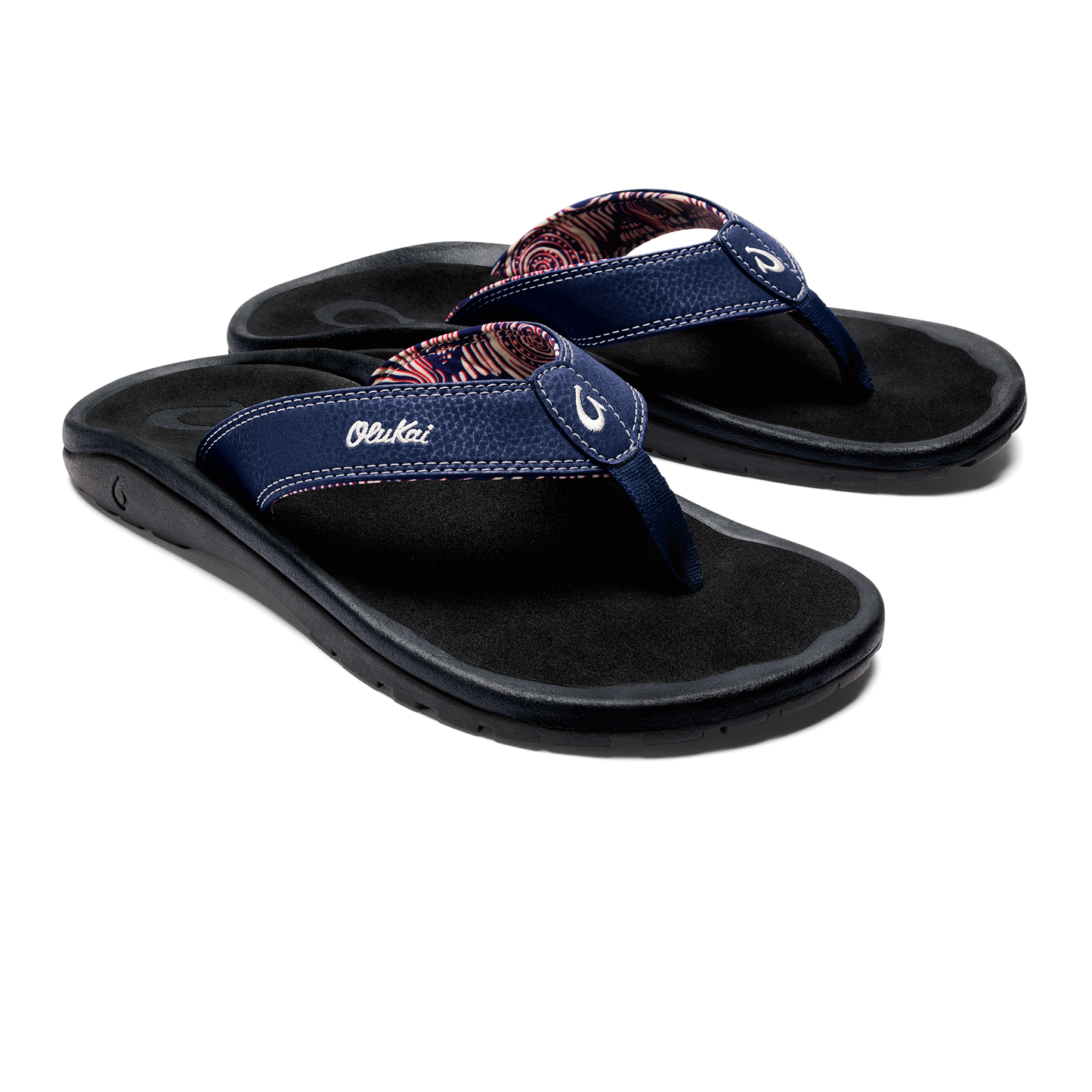 A pair of navy blue flip-flops with paisley print on straps and white text 'Olukai' on the side.