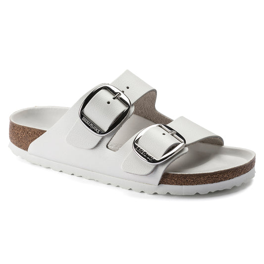 White sandal featuring two adjustable straps with large silver buckles and a cork sole.