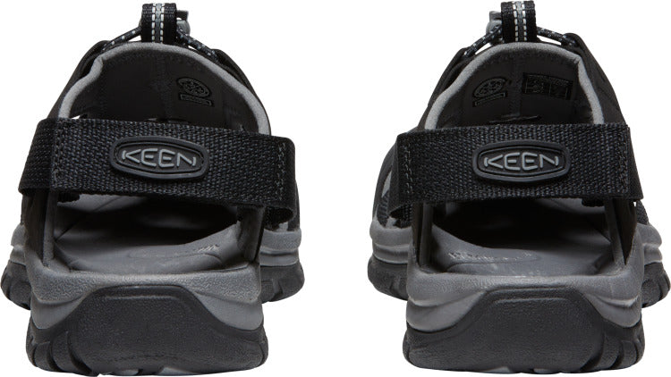 A pair of sandals with black straps and gray soles, showing the back view with KEEN logo on the strap.