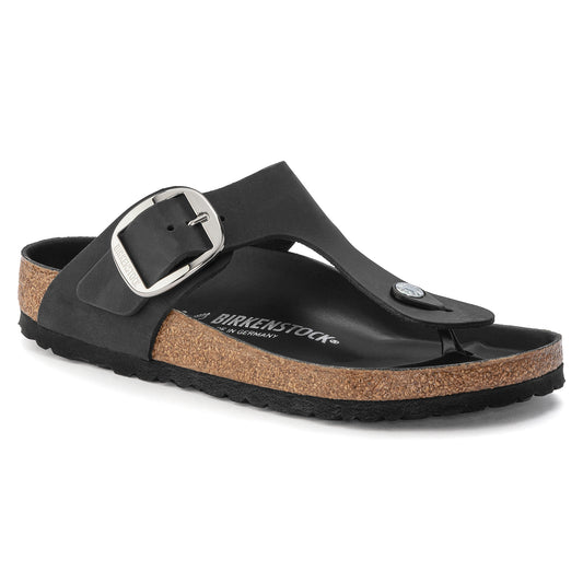 Black slide sandal with large adjustable buckle, cork sole, and toe post.