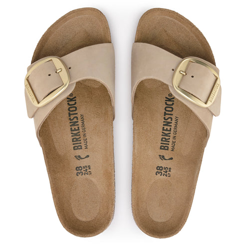 Pair of beige slide sandals with gold buckles, "BIRKENSTOCK" printed inside.