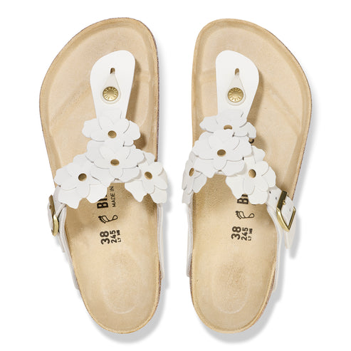 Overhead view of two white sandals with flower accents.