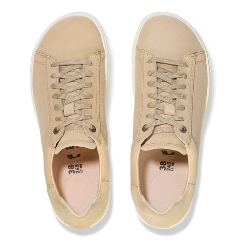 Top-down view of two tan leather sneakers with white soles and tan laces.