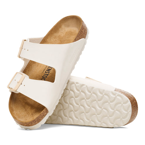 Two off-white sandals with two straps, buckle closures, and cork insoles.