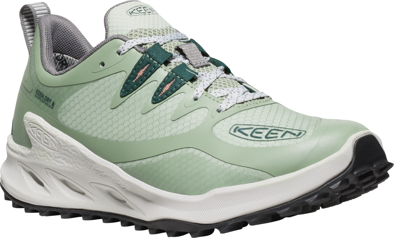 A sage-green shoe with dark-green accents and white soles, visible lacing and grey padded interior.