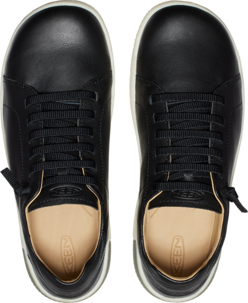A pair of black leather sneakers, top view, with white soles and beige insoles.