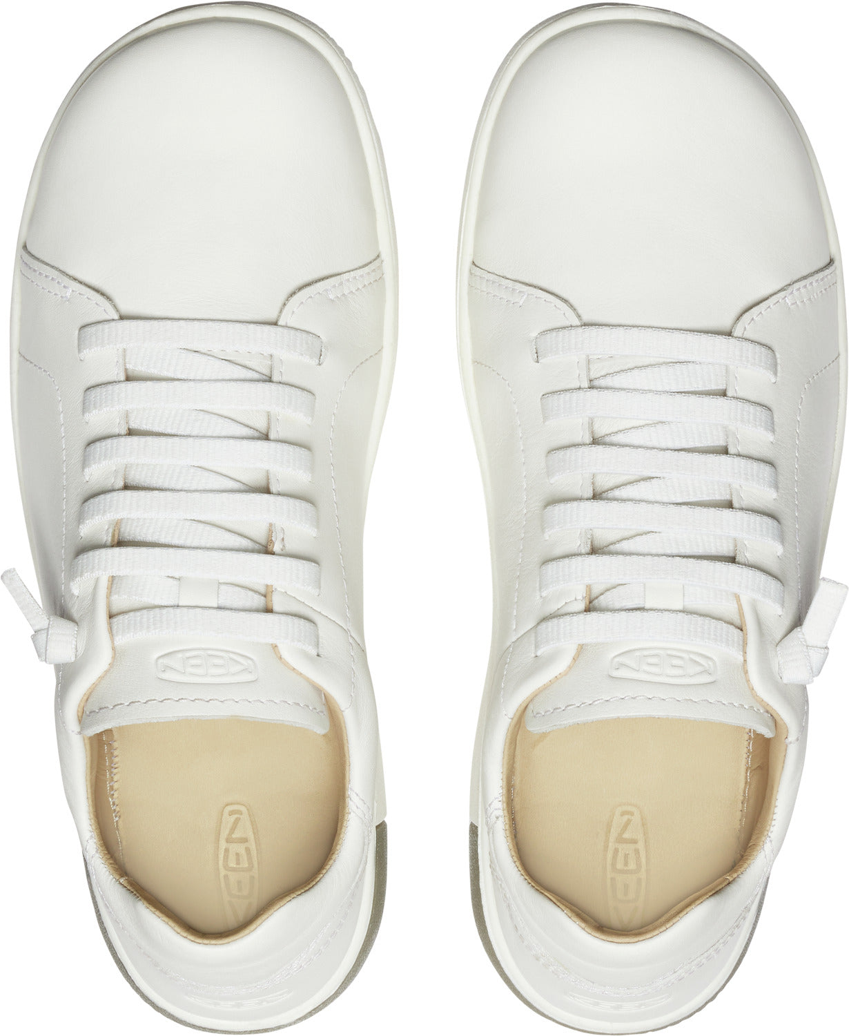 Overhead view of two white lace-up sneakers; leather upper, round toe, and a beige insole.