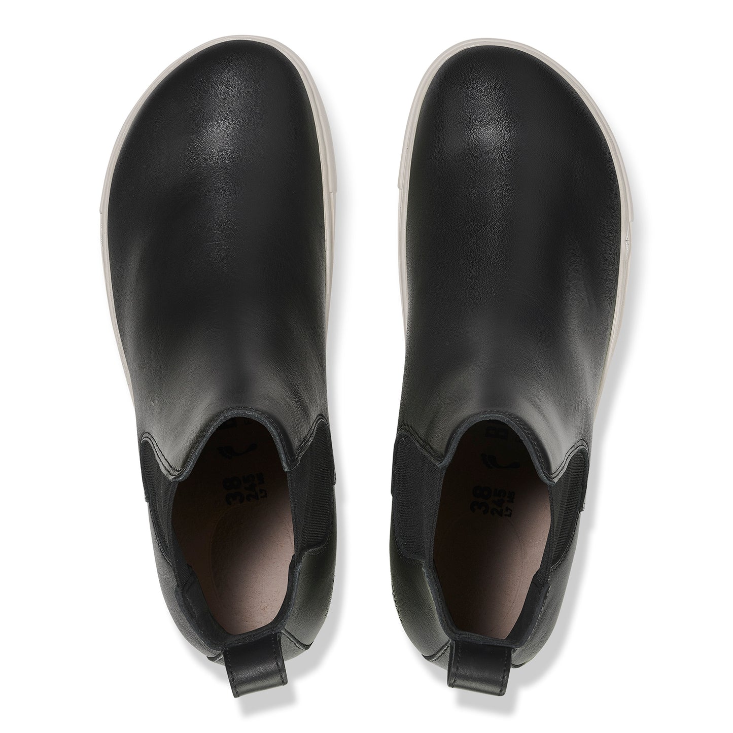 Overhead view of a pair of black leather Chelsea boots with white soles and elastic side panels.