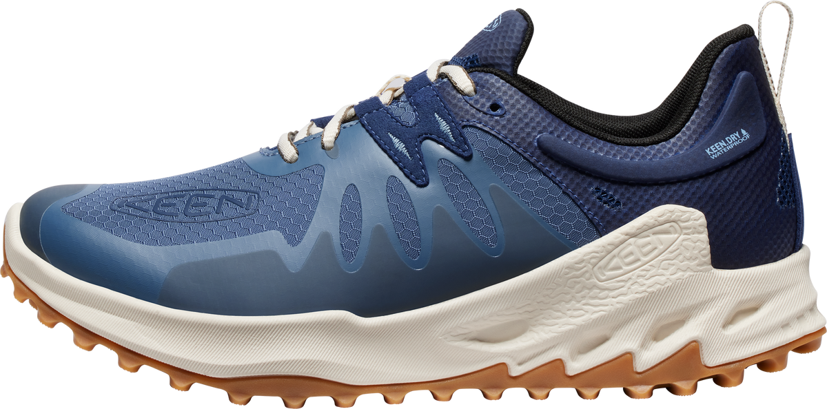 A blue and tan trail running shoe with white laces.