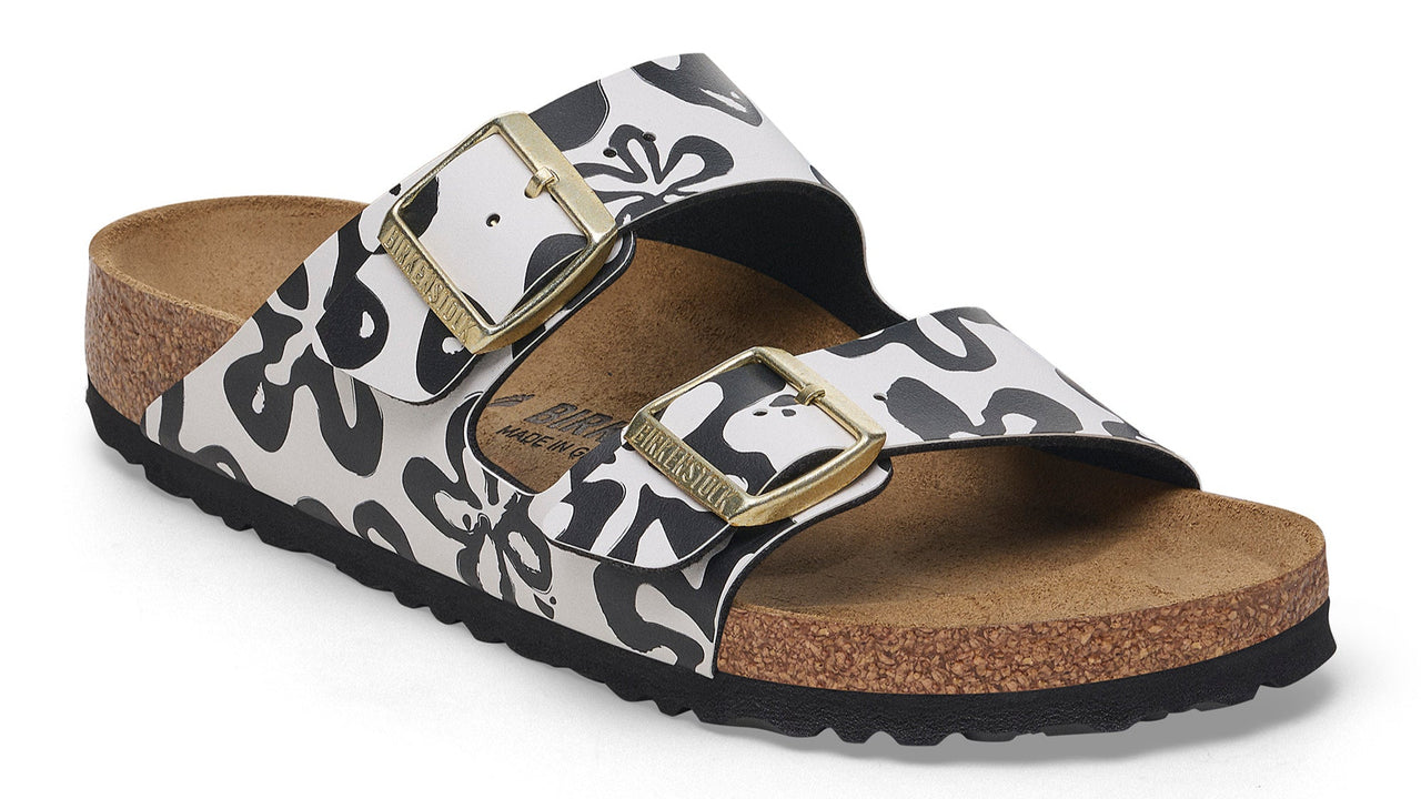 Sandals with two adjustable straps featuring a bold black and white floral pattern and gold buckles.