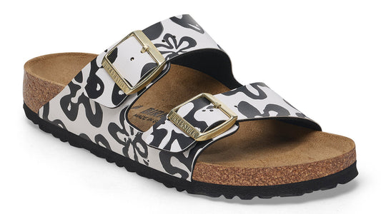 Sandals with two adjustable straps featuring a bold black and white floral pattern and gold buckles.