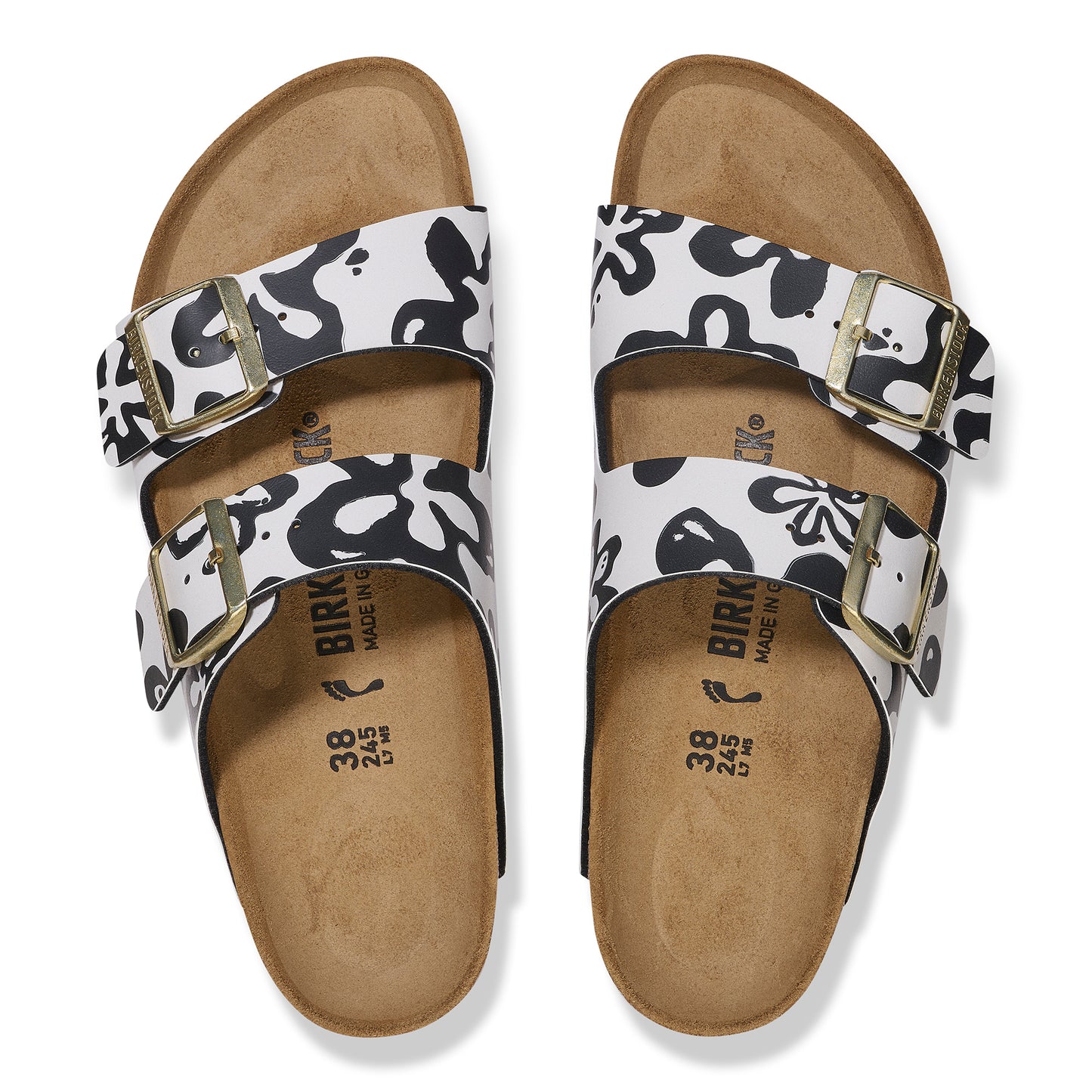 Top-down shot of Birkenstock Arizona sandals featuring black and white floral pattern straps and gold buckles. 'BIRK' text is visible on the footbed.