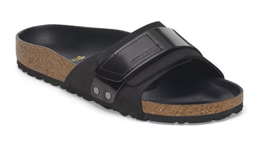 Black slide sandal with a cork sole and a shiny black adjustable strap.