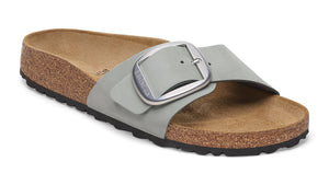 Slide sandal with a large silver buckle and cork sole.