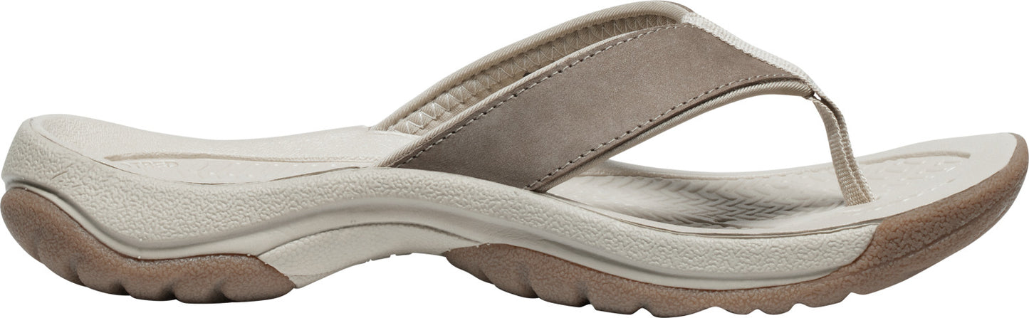A tan flip-flop sandal features a beige sole, a textured brown outer sole, and a thick tan toe strap.