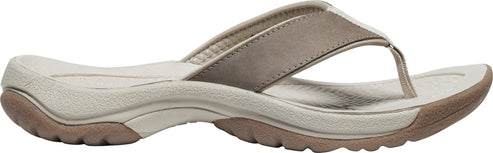 A tan flip-flop sandal features a beige sole, a textured brown outer sole, and a thick tan toe strap.