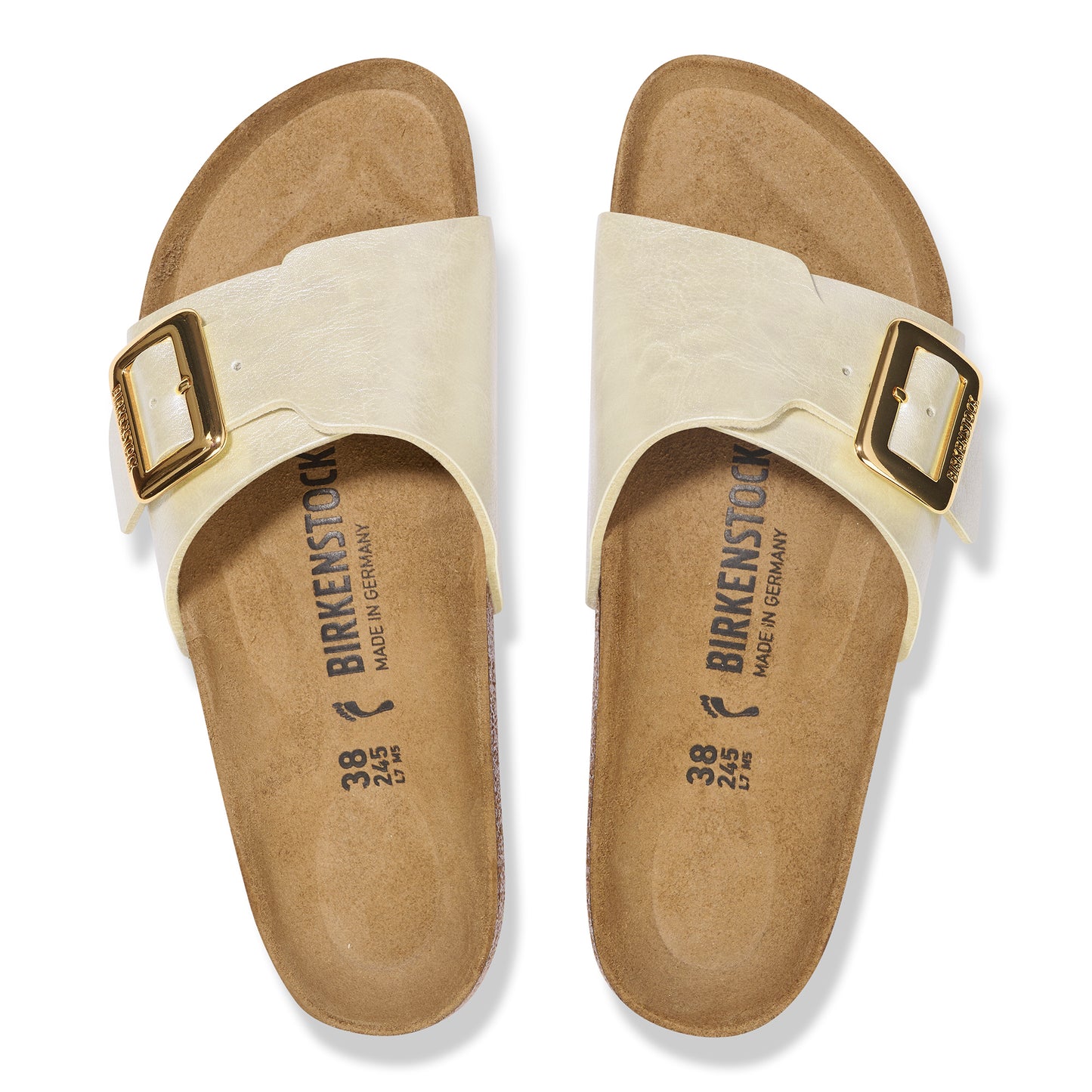 Pair of cream-colored sandals with adjustable gold-tone buckles and visible "BIRKENSTOCK MADE IN GERMANY" imprint on footbed.