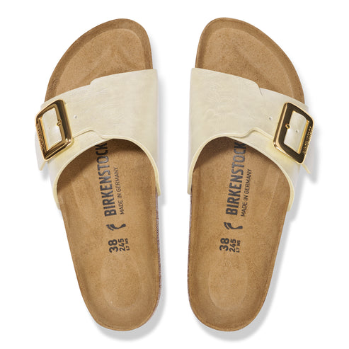 Pair of cream-colored sandals with adjustable gold-tone buckles and visible "BIRKENSTOCK MADE IN GERMANY" imprint on footbed.